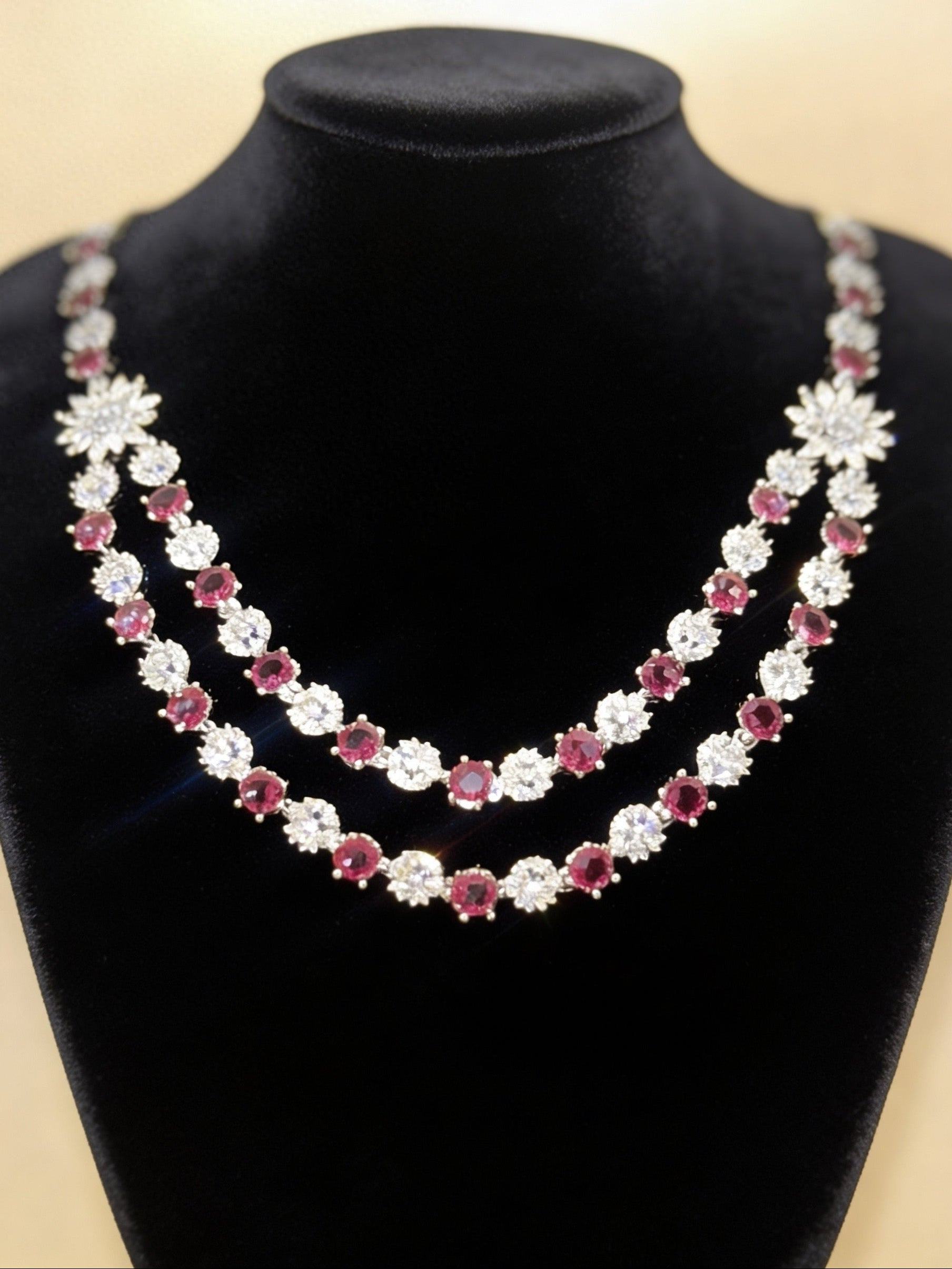 Double-strand necklace featuring ruby red stones and white American diamonds with a sunburst centrepiece. Elegant bridal jewellery for weddings, sangeet, and special occasions.